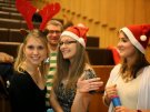 3 studentów medycyny przebranych w czapki mikołajowe oraz studentka przebrana za renifera Świętego Mikołaja. . 