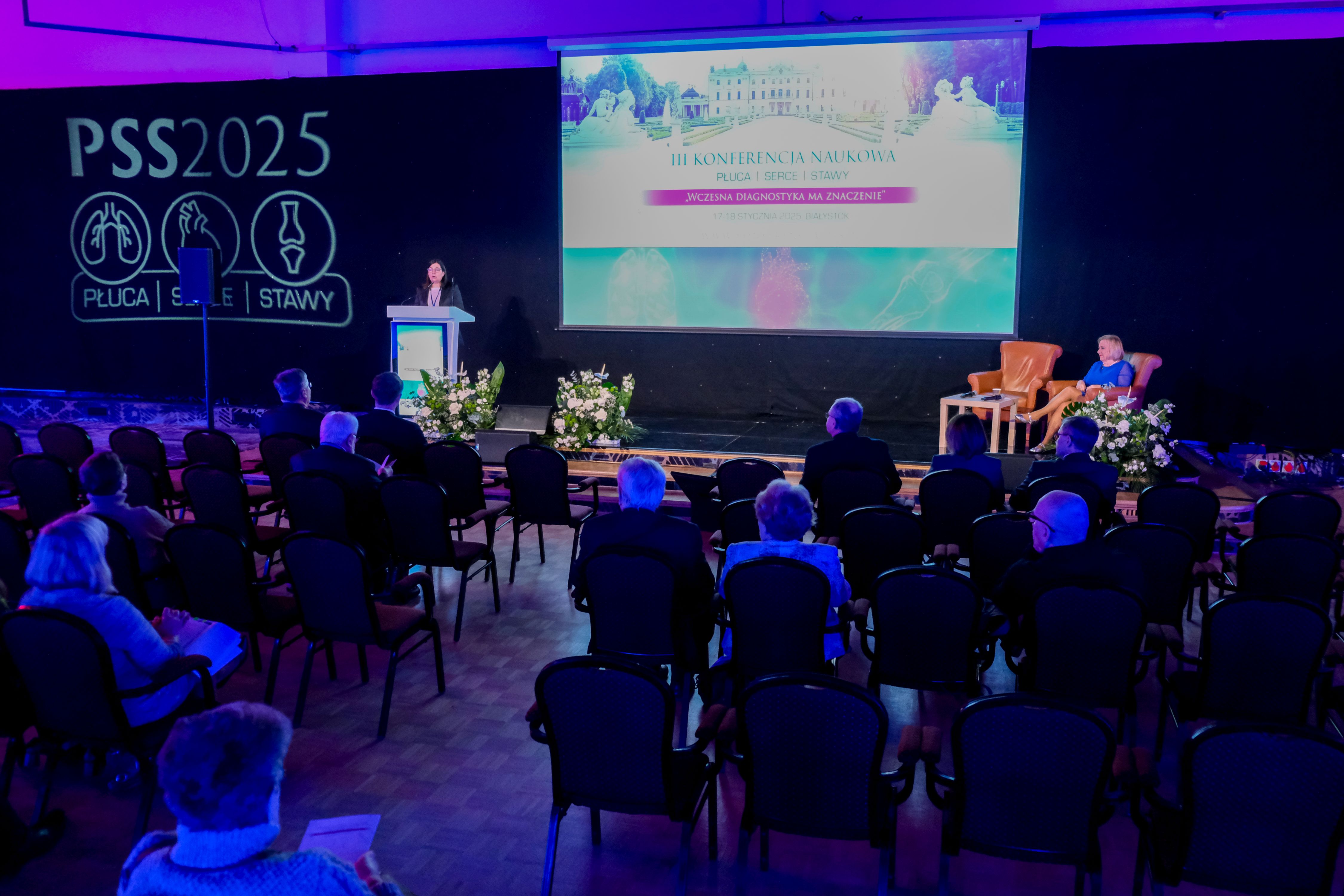 zdjęcie pokazuje scenę, mównicę oraz zgromadzonych na konferencji uczestników