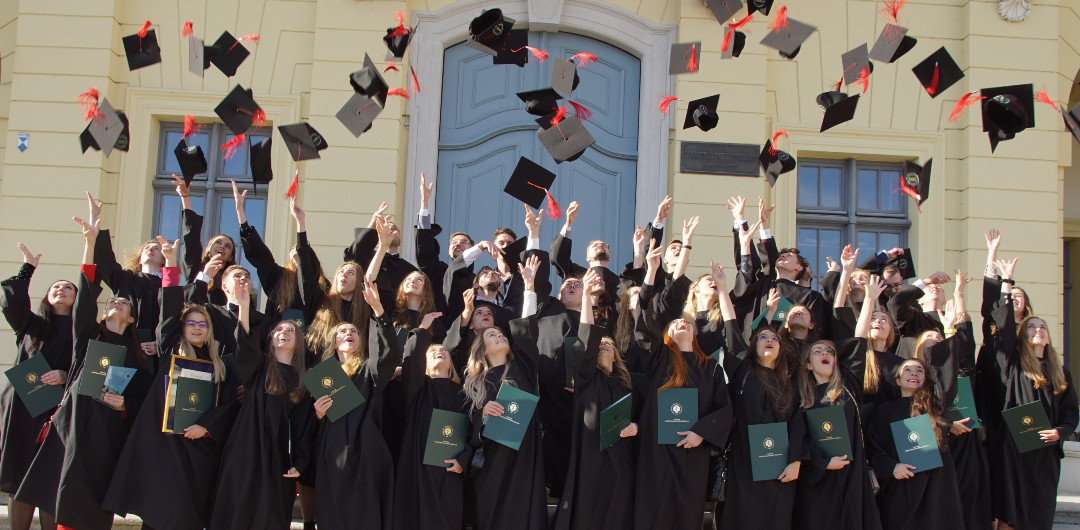 Absolwenci UMB z roku 2021 kierunku lekarsko-dentsytycznego podrzucają birety przed wejściem do Pałacu Branickich w Białymstoku.